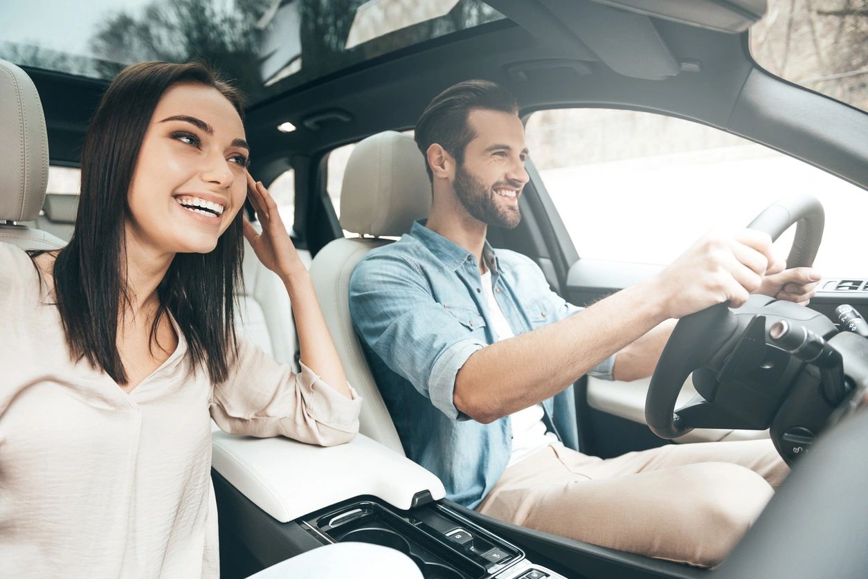 Happy couple inside car smiling